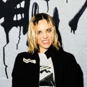 Jehnny Beth smiling infront of graffiti wall